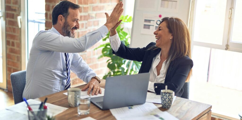 Begeisterter Kunde und Berater geben sich im Büro ein High Five